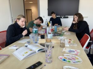 A group of adults during an in-class painting and watercolor workshop, a time for artistic development and socializing.