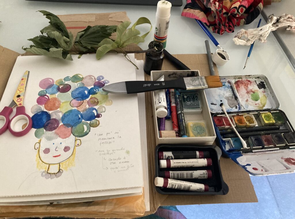 A view of a chaotic yet creative artist's work table, featuring a portrait of a woman with watercolor-splattered hair, professional brushes, a color palette, pastels, ink bottles, scissors, and real leaves.